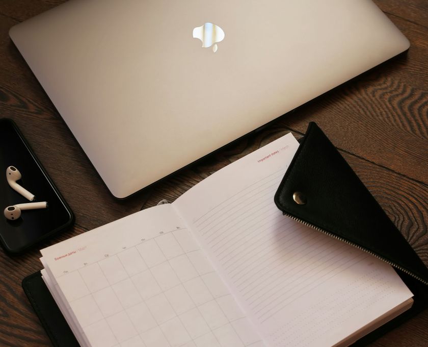 Flat lay of a laptop, smartphone, notepad, and icons representing business tools